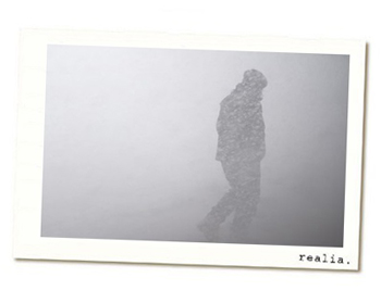 A bundled up person barely visible walking in a snowstorm